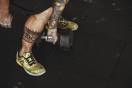 person in brown Reebok sneakers holding black steel dumbbells thumbnail