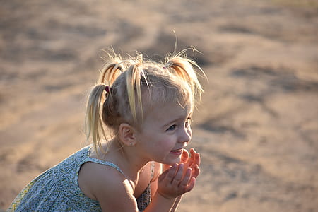 girl sitting on sand during daytime thumbnail