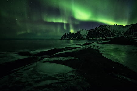 body of water near brown and white mountain under Aurora lights thumbnail