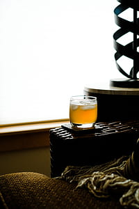 clear shot glass filled with yellow liquid with ice on brown rack thumbnail