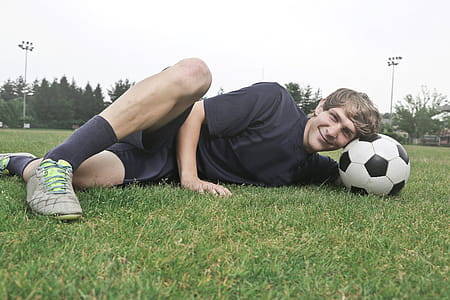 Man Wearing Black Crew-neck Shirt and Black Shorts Lying on Green Grass at Daytime thumbnail