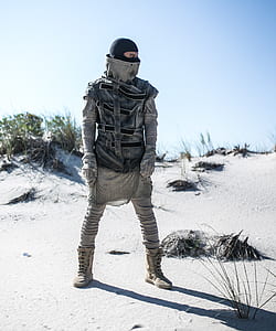 person in gray and black suit standing on white desert during daytime thumbnail