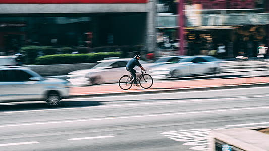 selective focus photo of person riding on bicycle beside road thumbnail