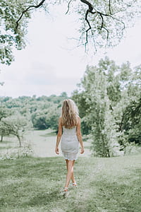 shallow focus photography of woman in dress standing on green grass during daytime thumbnail