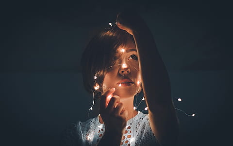woman wearing white lace top holding string of lights photography thumbnail