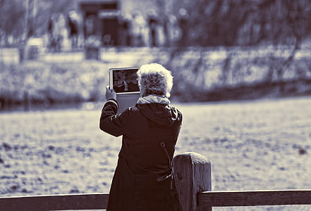 woman taking photo of pond during daytime thumbnail