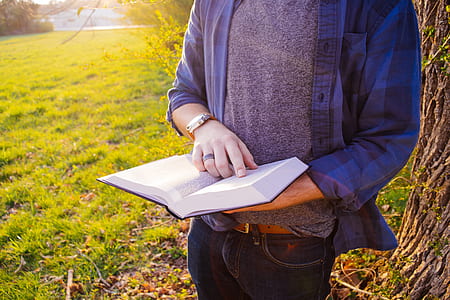man in gray top reading book during daytime thumbnail