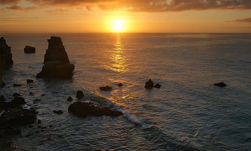rock formation in body of water at golden hour thumbnail