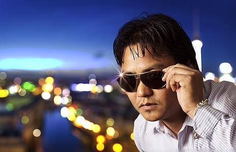 man holding black lens sunglasses with gray frame thumbnail