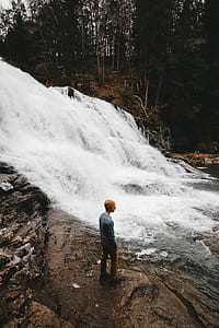man standing near waterfalls thumbnail