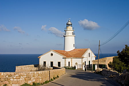 white and brown concrete house and white lighthouse beside water during daytime thumbnail