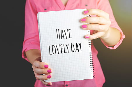 Woman Wearing Pink Dress Holding Graphing Notebook With Have a Lovely Day Sign thumbnail