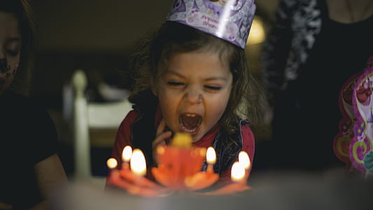girl blowing candle on cake inside the house thumbnail