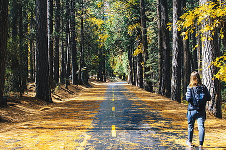 woman in black jacket and pants walking on asphalt road thumbnail