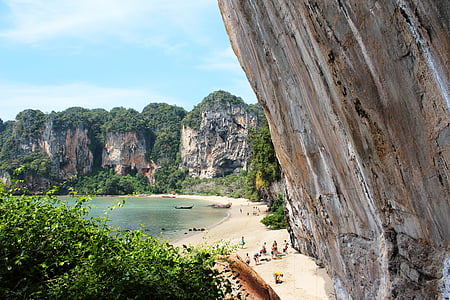people on seashore surrounded by rocky mountains thumbnail