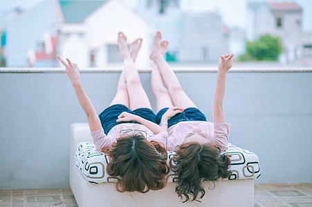 two girl's wearing same shirts and shorts lying down on roof top thumbnail