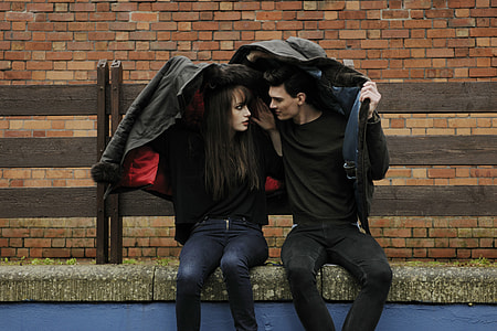 man and woman sits on beige concrete bench in front of beige concrete brick wall thumbnail