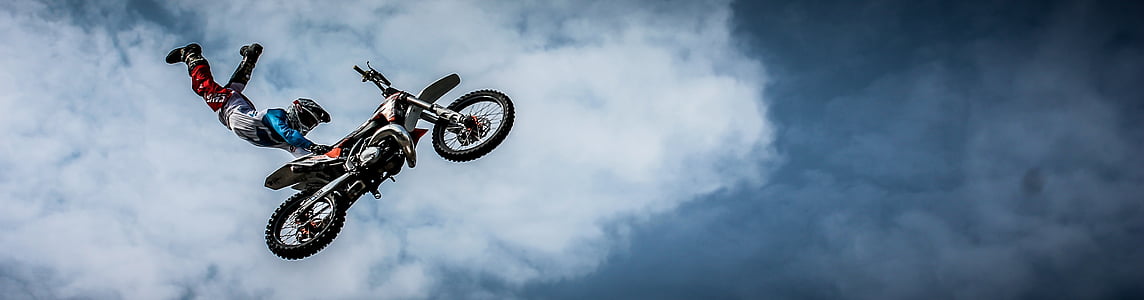 sports photography of motocross racer holding motocross dirt bike seat while suspended on air thumbnail