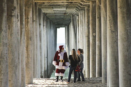 two woman standing in front of Santa Claus during daytime thumbnail