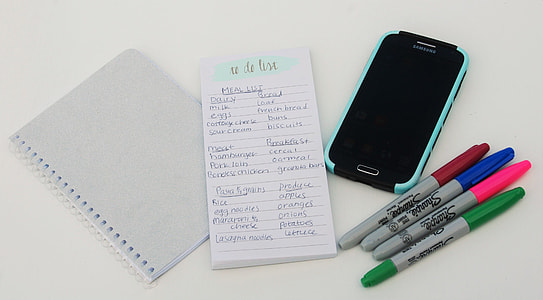 black Samsung android smartphone beside four Sharpie markers and two notepads thumbnail