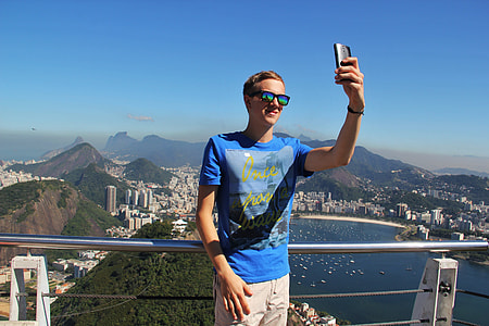 man leaning on gray steel railing taking a selfie at daytime thumbnail