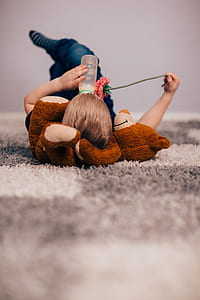 child lying bear plush toy while drinking on bottle thumbnail