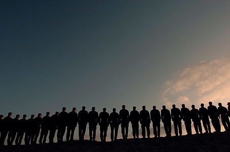 silhouette of men standing under gray skies thumbnail