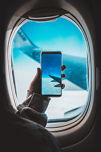 person holding black Android smartphone taking photo of left airliner wing thumbnail