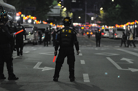 cops standing on road with people walking during nighttime thumbnail