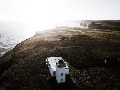 white concrete house on mountain beside body of water thumbnail