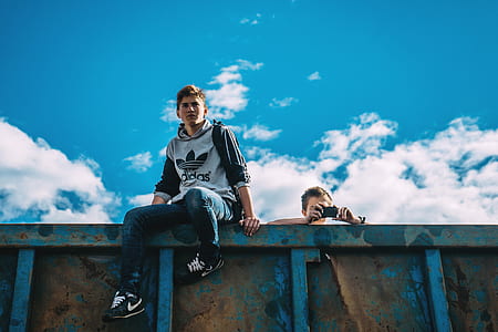 two men sitting on top of blue fence thumbnail
