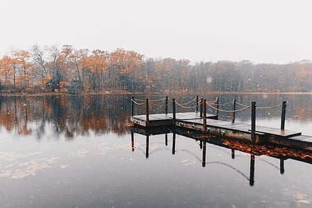 brown wooden dock on lake under bright sky thumbnail