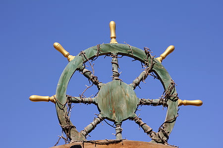 green and brown wooden ship's helm under blue clear sky during daytime thumbnail