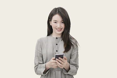 Woman in Gray Button-up Long-sleeved Dress Holding Black Smartphone thumbnail
