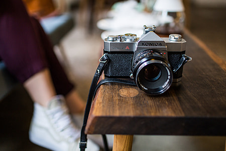 black and gray Konica SLR camera on table thumbnail