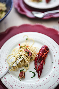 Fancy dinner with seafood pasta, crayfish and red wine by the table decorated with roses thumbnail