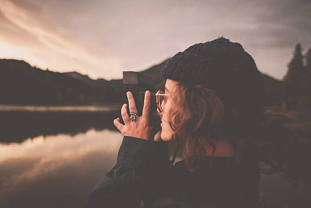 selective focus of woman holding camera while taking picture thumbnail