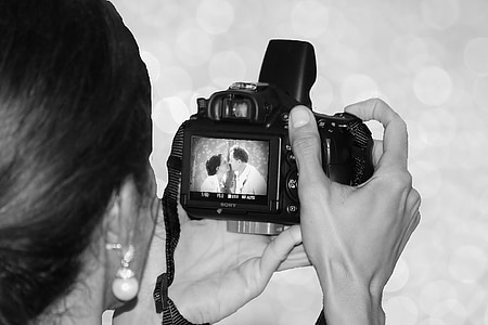 grayscale photo of person holding DSLR camera thumbnail
