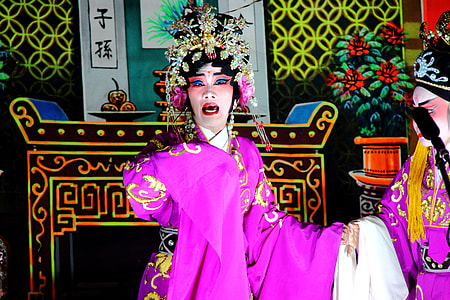 singing woman wearing pink and white traditional dress and gold-colored headpiece thumbnail