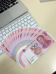 Macbook with a fan of chinese hundred dollar bills thumbnail