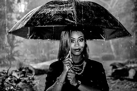 grayscale shallow focus photography of woman holding umbrella under rain thumbnail
