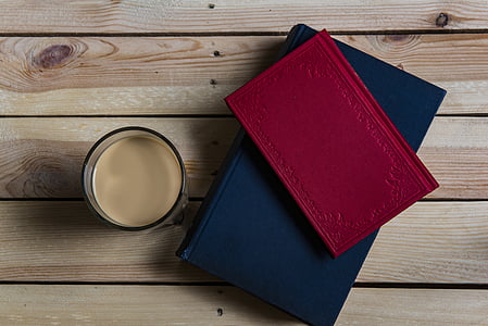 two books beside drinking glass filled with brown liquid thumbnail