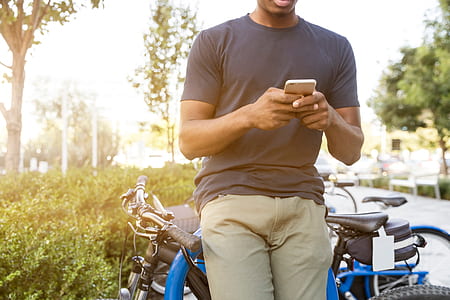 man wearing gray crew-neck t-shirt holding smartphone thumbnail