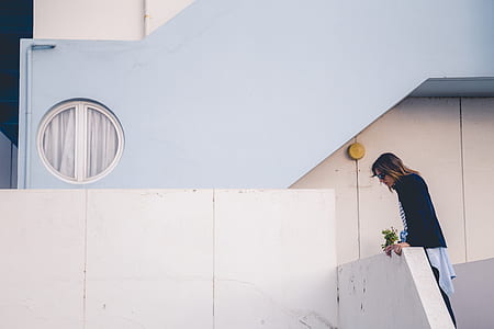 woman in black cardigan looking down near gray concrete stairs thumbnail