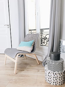 white and blue pillow placed on gray chair near window thumbnail