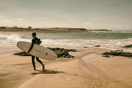 A surfer walks along the beach on the coast of Cornwall, England. Image captured with a Canon 5D DSLR thumbnail