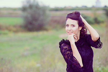woman standing on green grass while hand on chin and hair thumbnail