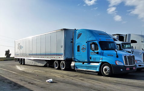 two blue and white freight truck parks in parking lot at daytime thumbnail