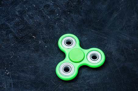 green 3-blade fidget spinner on black surface thumbnail