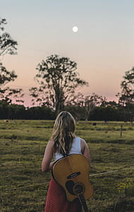 woman in white and red sleeveless dress standing near field fence thumbnail